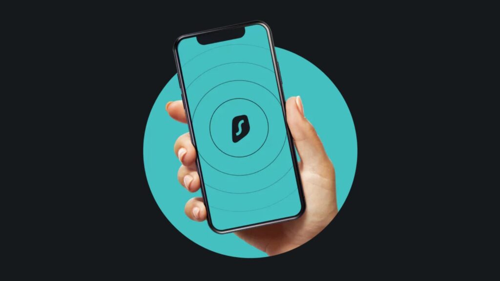 A hand holding a smartphone featuring the logo of Surfshark VPN.