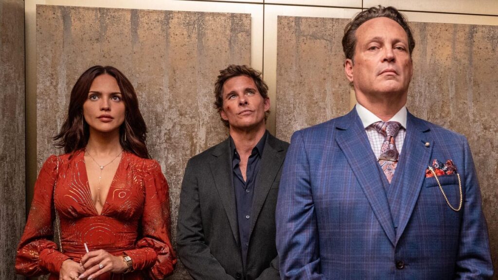 Hulu’s New Crime Caper Comedy Is a Raucous Shoot ‘Em Up Throwback Production still from Mike & Nick & Nick & Alice showing Eiza Gonzales in a red dress standing next to James Marsden and Vince Vaughn in an elevator.