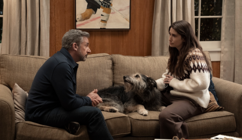 Steve Carell and Charly Clive sitting on a sofa with a dog between them in HBO's Rooster