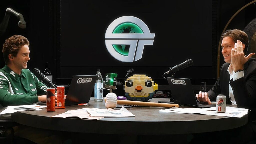 The two hosts of the TBPN show chat at their desk.