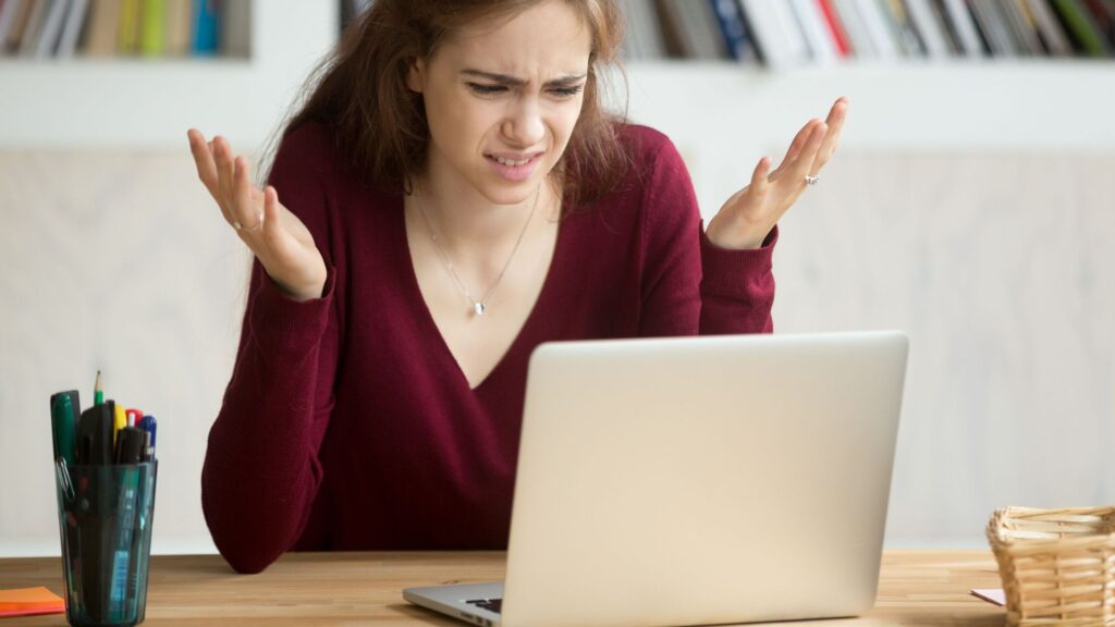 A woman looking frustrated seeing price hikes on her laptop screen