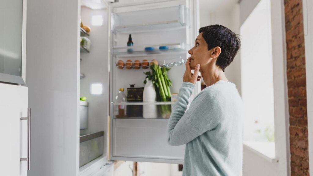 Your Old Fridge Is Costing You. Here’s How Much Energy a New Model Saves Each Year women looking into open fridge
