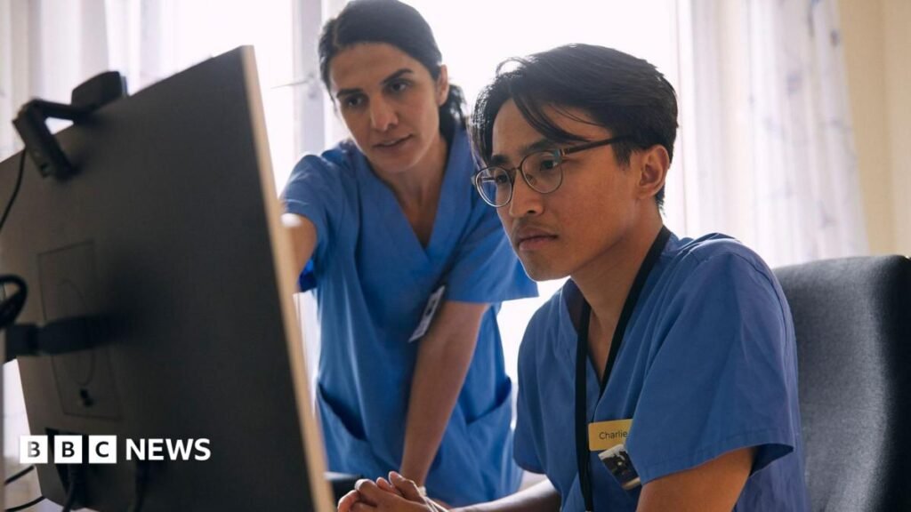 Consultants in England vote in favour of NHS strikes Two doctors wearing surgical scrubs look at a computer monitor and chat about what they are examining