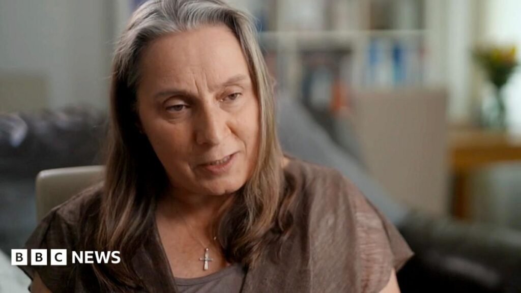 Denise Howarth has long hair and is looking to the right, off camera