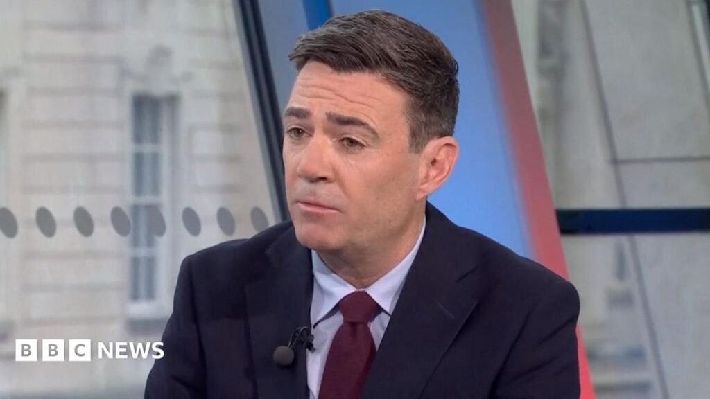 Andy Burnham from the shoulders up in a suit and maroon tie
