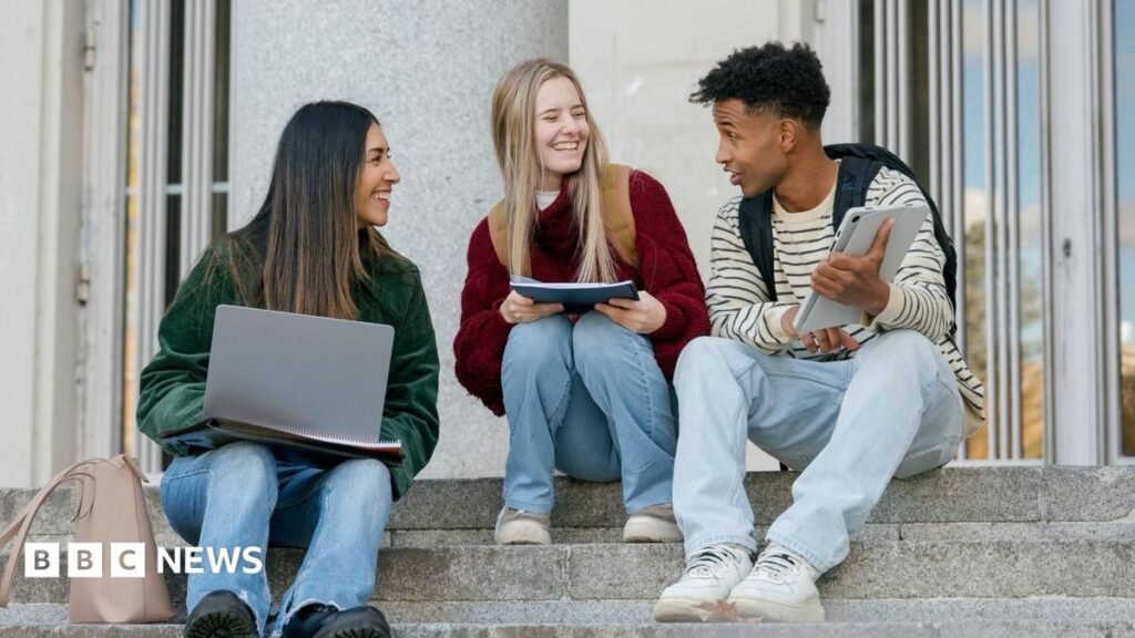Social anxiety: The hidden habits that make it worse – and how you can break them Three university students sitting on concrete stairs, talking and smiling while looking at a digital tablet and laptop. There are two women to the left both looking at a male student to the right.